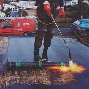 Curt Marshall heats the roofing felt with his gas torch to ensure a watertight seal.